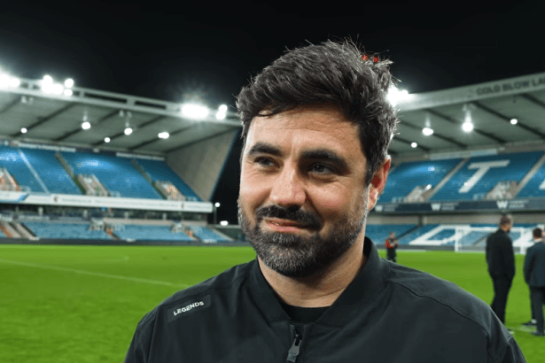 Swansea City head coach Vitor Matos smiling on the pitch at the Den after the win at Millwall