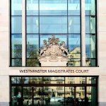 The glass and stone frontage of Westminster Magistrates Court in London, with the royal coat of arms above the entrance