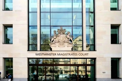 The glass and stone frontage of Westminster Magistrates Court in London, with the royal coat of arms above the entrance