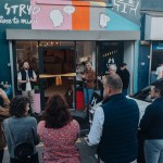 A crowd gathers in the street for the opening of Y Stryd, a cafe with a colourful mural, next door to Llanelli Mind