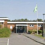 The entrance to Ysgol Heol Goffa special school in Llanelli, a single-storey brick building with a green flag flying outside