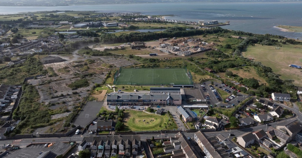 Aerial view of Ysgol Pen Rhos primary school in Llanelli and its green 3G pitch, with the AMG Resources waste site and the Loughor estuary beyond